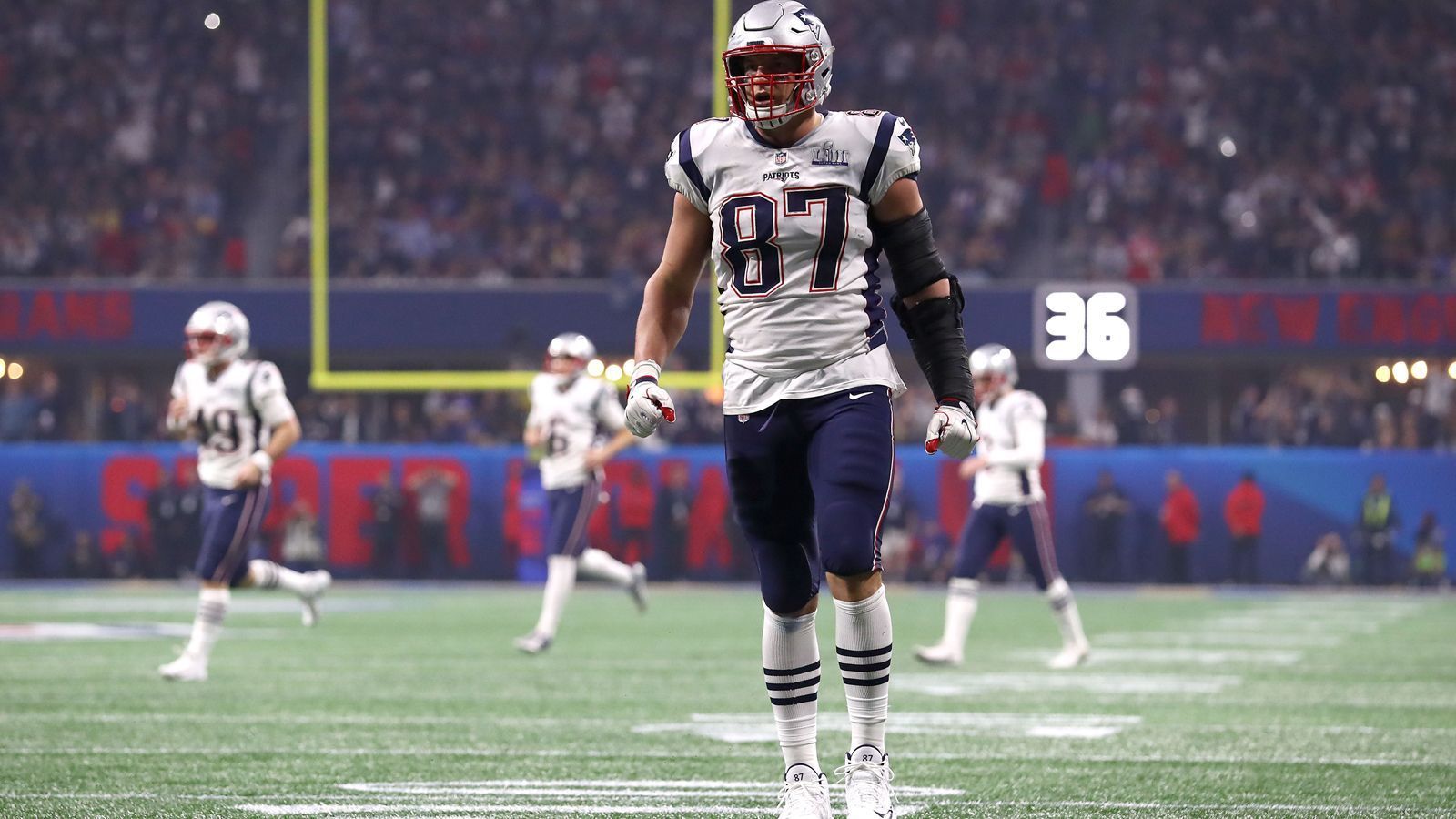 
                <strong>Rob Gronkowski</strong><br>
                Ein kleiner Trade mit großen Auswirkungen: Inmitten des NFL-Drafts 2010 tradet Bill Belichick einen Sechstrunden-Pick und und einen Zweitrunden-Pick für den Zweitrunden-Pick der Oakland Raiders. Die Patriots rücken zwei Plätze nach vorne und wählen an 42. Stelle einen Tight End von der Arizona University: Rob Gronkowski. "Gronk" dominiert die NFL, fängt in seiner Karriere 521 Pässe für 7861 Yards und 79 Touchdowns. Der 30-Jährige kündigt in dieser Offseason 2019 sein Karriereende an und blickt auf eine sehr erfolgreiche Zeit mit den Patriots zurück.
              