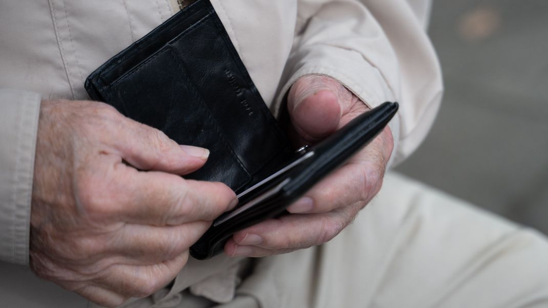 Ein Rentner hält sein Portemonnaie in der Hand