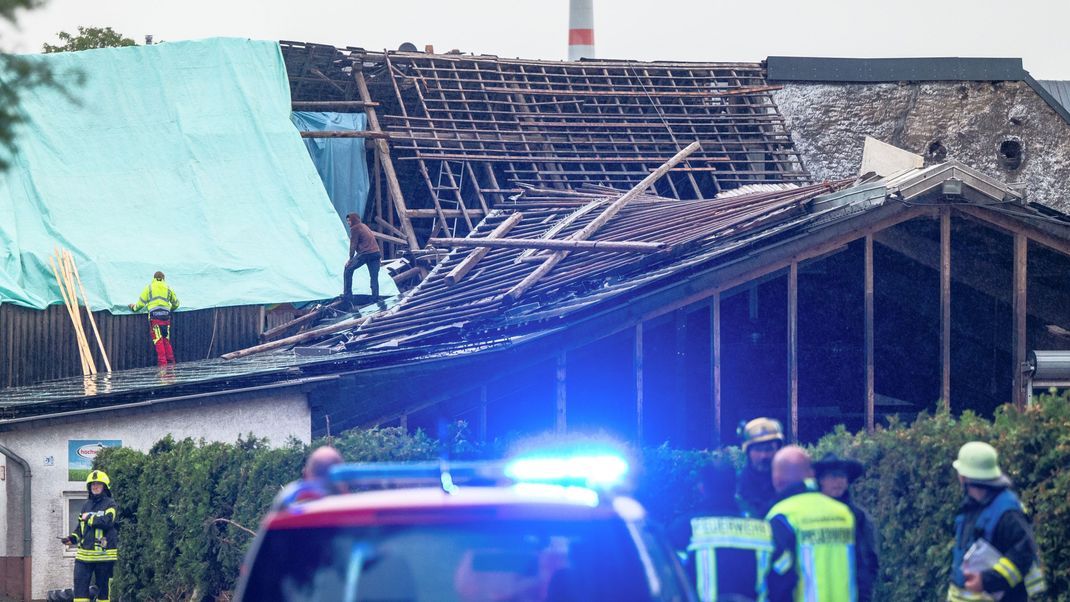 Einsatzkräfte sichern das zerstörte Dach eines Hauses in Nusbaum mit Planen gegen das Unwetter.