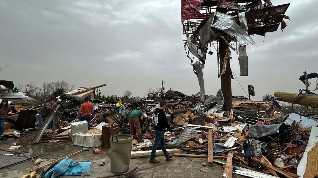 Menschen arbeiten sich durch die Trümmer des Geschäfts von Cave City Auto Parts nach einem schweren Unwetter in Cave City, Ark. 