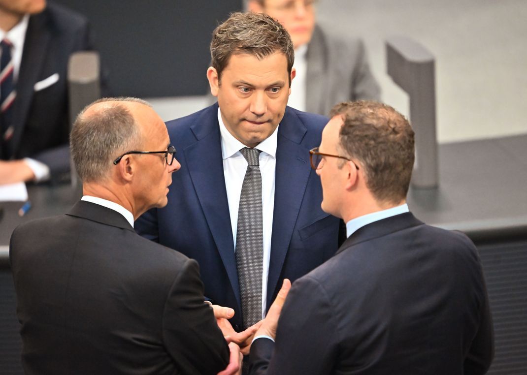 Der designierte Bundeskanzler Friedrich Merz (CDU, links) spricht im Bundestag bei der Kanzlerwahl mit Lars Klingbeil (SPD, Mitte), designierter Bundesminister der Finanzen, und dem Vorsitzenden der Unionsfraktion, Jens Spahn (CDU).