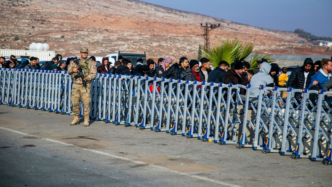 Ein türkischer Soldat steht Wache, während Syrer am Cilvegozu-Grenzübergang in der Nähe der südtürkischen Stadt Antakya darauf warten, von der Türkei nach Syrien zu gelangen. 