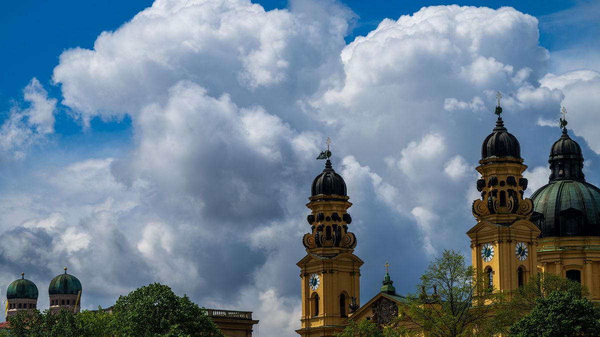 Wolken sind hinter den Türmen der Frauenkirche (l) und der Theatinerkirche (r) am Himmel zu sehen.