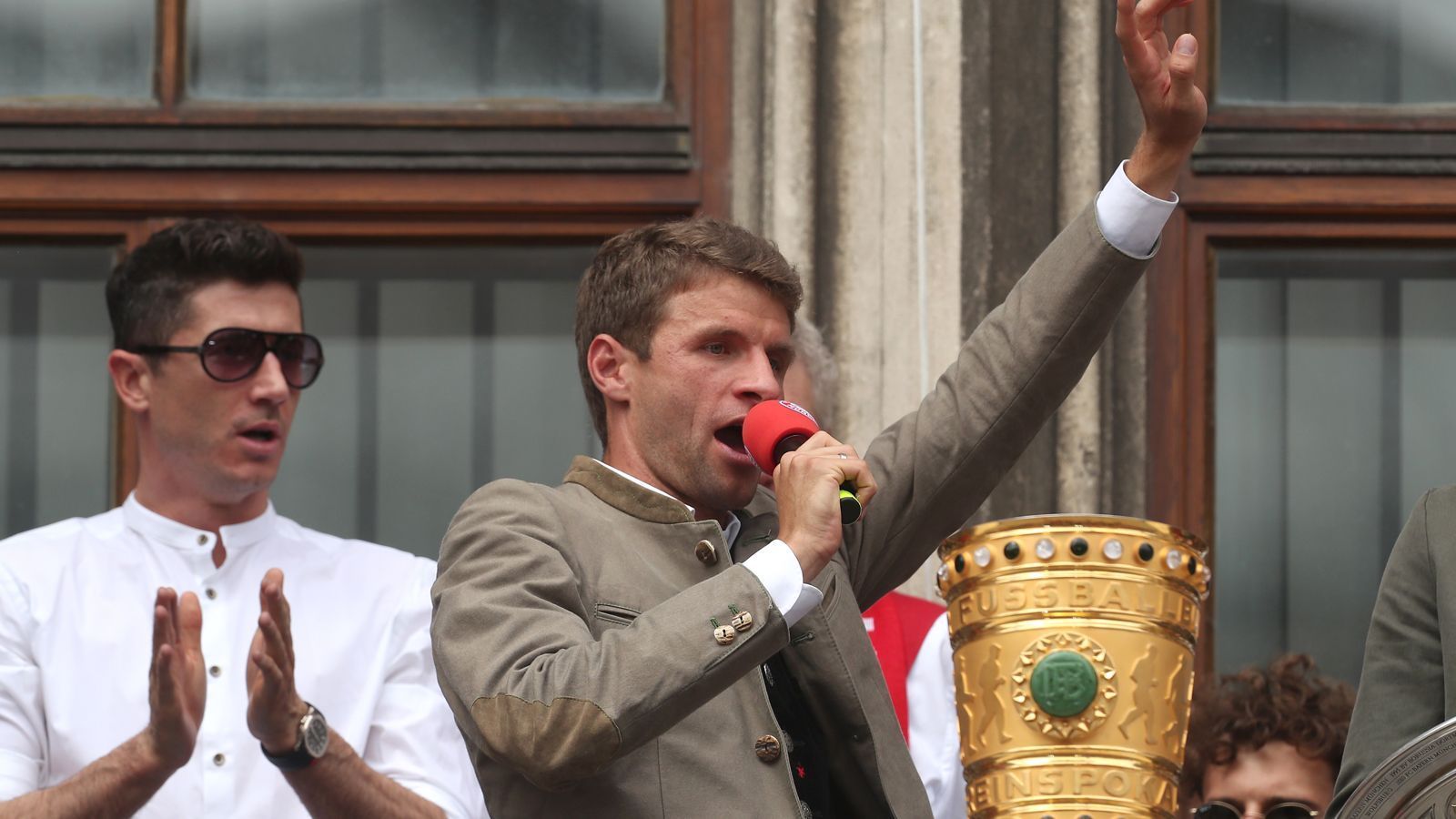 
                <strong>Double und Aufstieg der Amateure: Die Bayern feiern</strong><br>
                Größter Stimmungsmacher auf dem Balkon war Thomas Müller. Mit dunkler Sonnenbrille und hörbar angeschlagener Stimme grölte er einige Minuten lang beliebte Fangesänge ins Mikro.
              