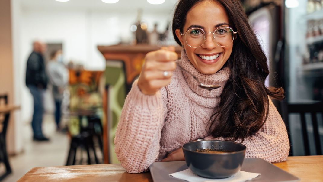 Happy woman, ordering a bowl of soup in a restaurant.