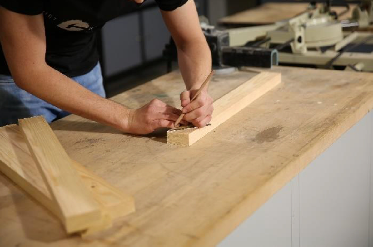 Damit der Tisch später einen festen Stand hat, müssen die Holzlatten passend zurechtgeschnitten werden. Dafür werden mit einem Geodreieck und Stift jeweils 45°-Winkel auf die Latten eingezeichnet.