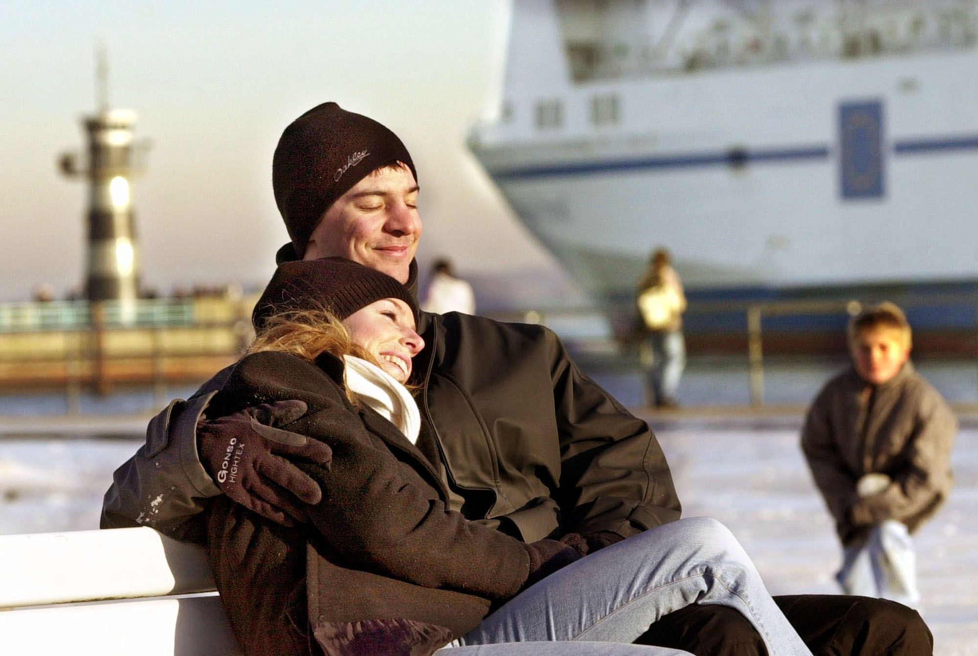 Paar kuschelt auf einer Bank am Hafen