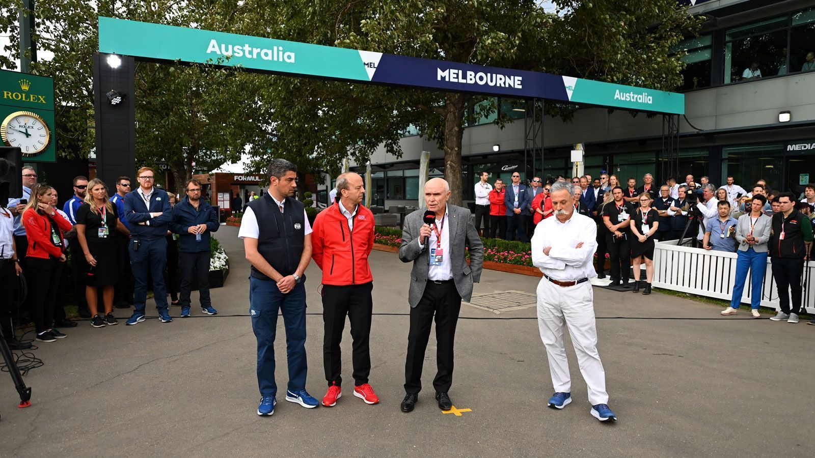 
                <strong>Melbourne: Das Ende vom Anfang</strong><br>
                Der traditionellen Saisonauftakt in Australien steht unter keinem guten Stern. Während sich die Corona-Pandemie weltweit ausbreitet, hält die Formel 1 am Rennen fest. Wenige Tage vor dem Start überschlagen sich dann die Ereignisse: Ein McLaren-Mechaniker wird positiv auf das Corona-Virus getestet, kurz darauf reist das gesamte Team aus Melbourne ab. Während tausende Fans ungeduldig vor den Eingängen warten, verkündet F1-Boss Chase Carey (vorne rechts) vor dem ersten Freien Training die Absage des Rennens am 15. März. Die Motoren bleiben für mehrere Monate still.
              