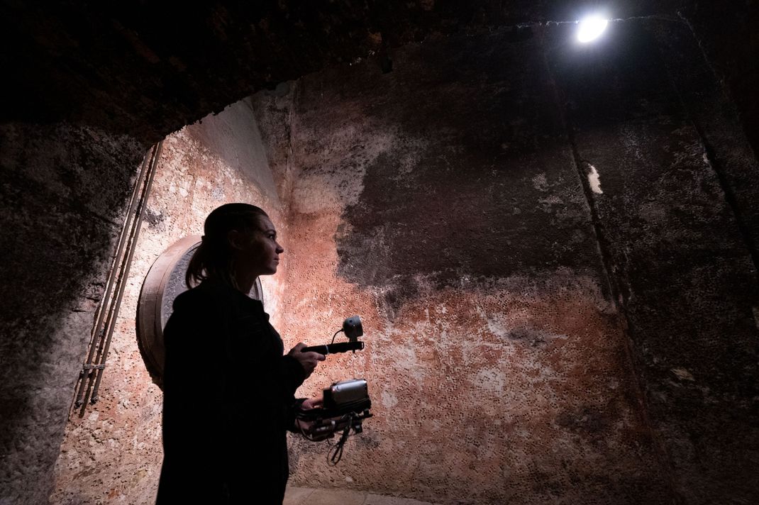 Eine Hobby-Geisterjäger:in geht in einem Schloss mit Kamera und Infrarotlicht auf Gespenstersuche.