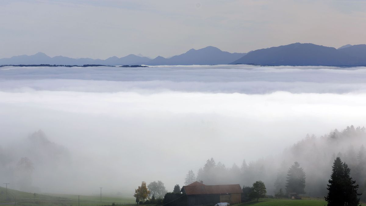 Nebel ist über der bayerischen Landschaft vor dem Panorama der Alpen zu sehen.