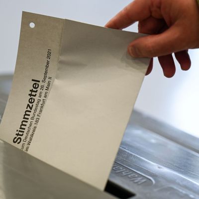 Stimmzettel wird in eine Wahlurne gesteckt