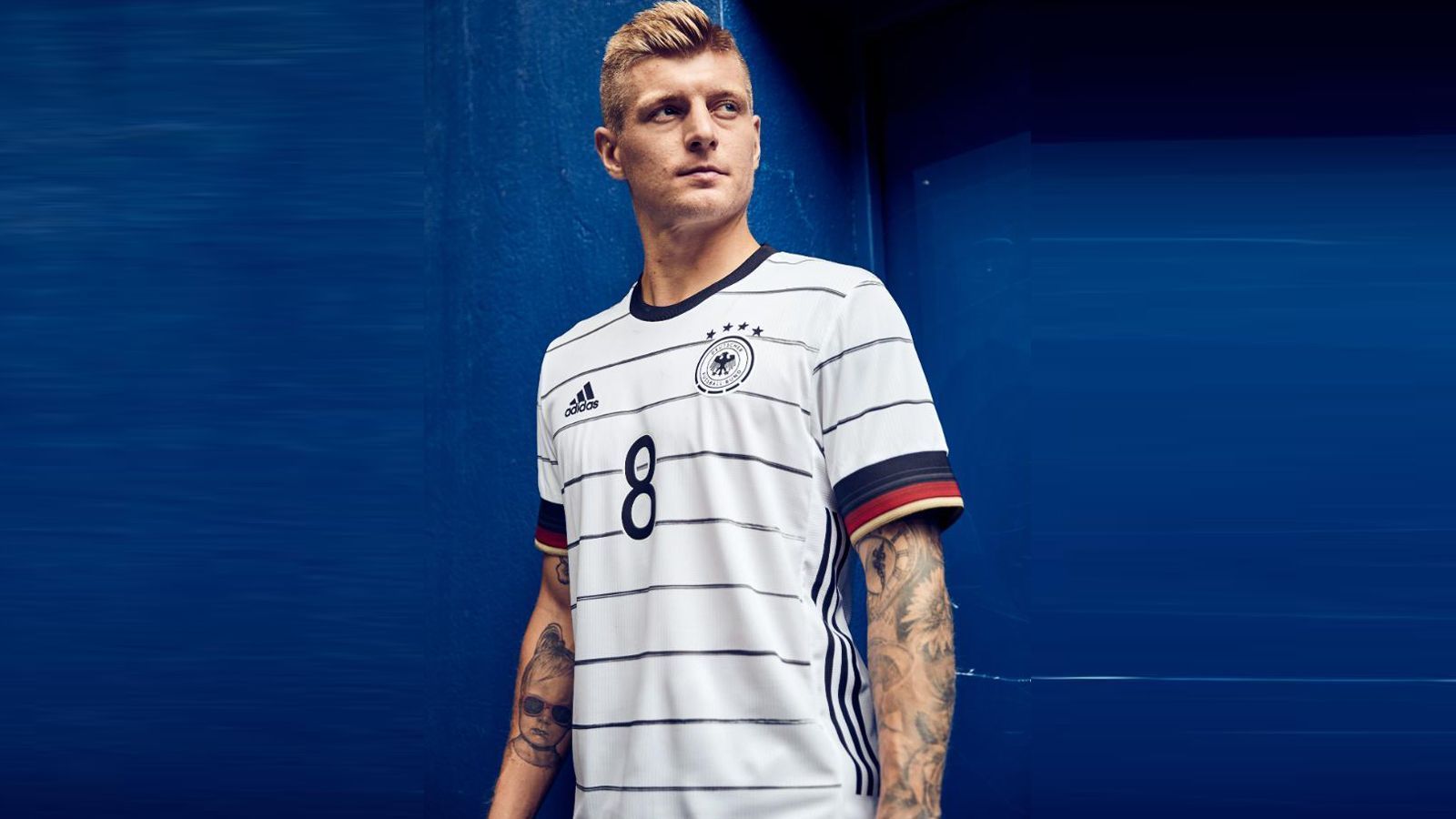 
                <strong>Germany</strong><br>
                Toni Kroos präsentiert das deutsche Trikot. Mit Nadelstreifen, aber ohne adidas-Streifen auf der Schulter. Dafür finden sich diese an der Seite wieder. Und der Kragen ist in Rundform.
              