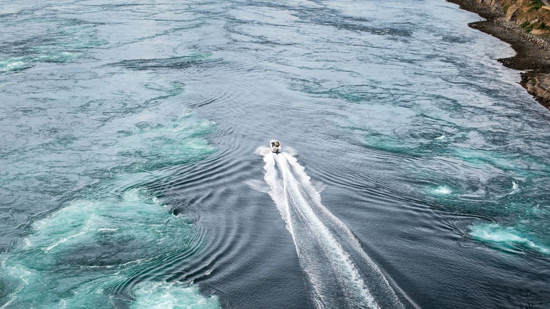 Eine Crew wagt mit einem Speedboot die Fahrt durch den Strom der Gezeiten in Norwegen. Dort bilden sich mehrere Wasserstrudel.