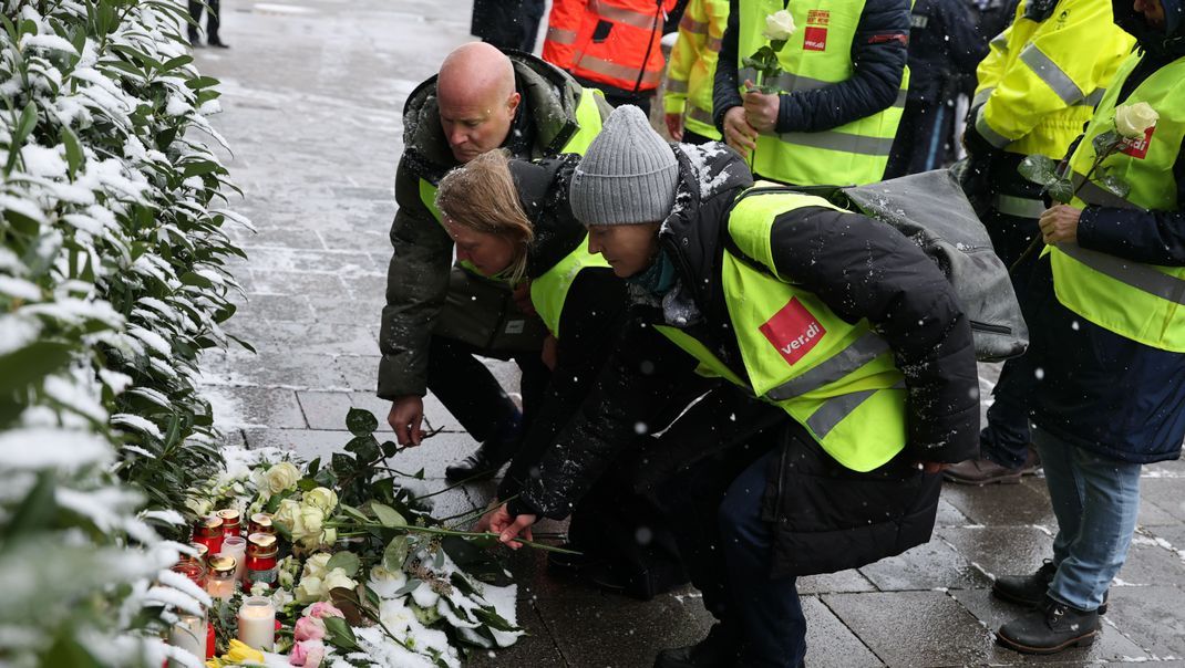 Gewerkschafter:innen von Verdi legen Blumen am Ort des Geschehens nieder.