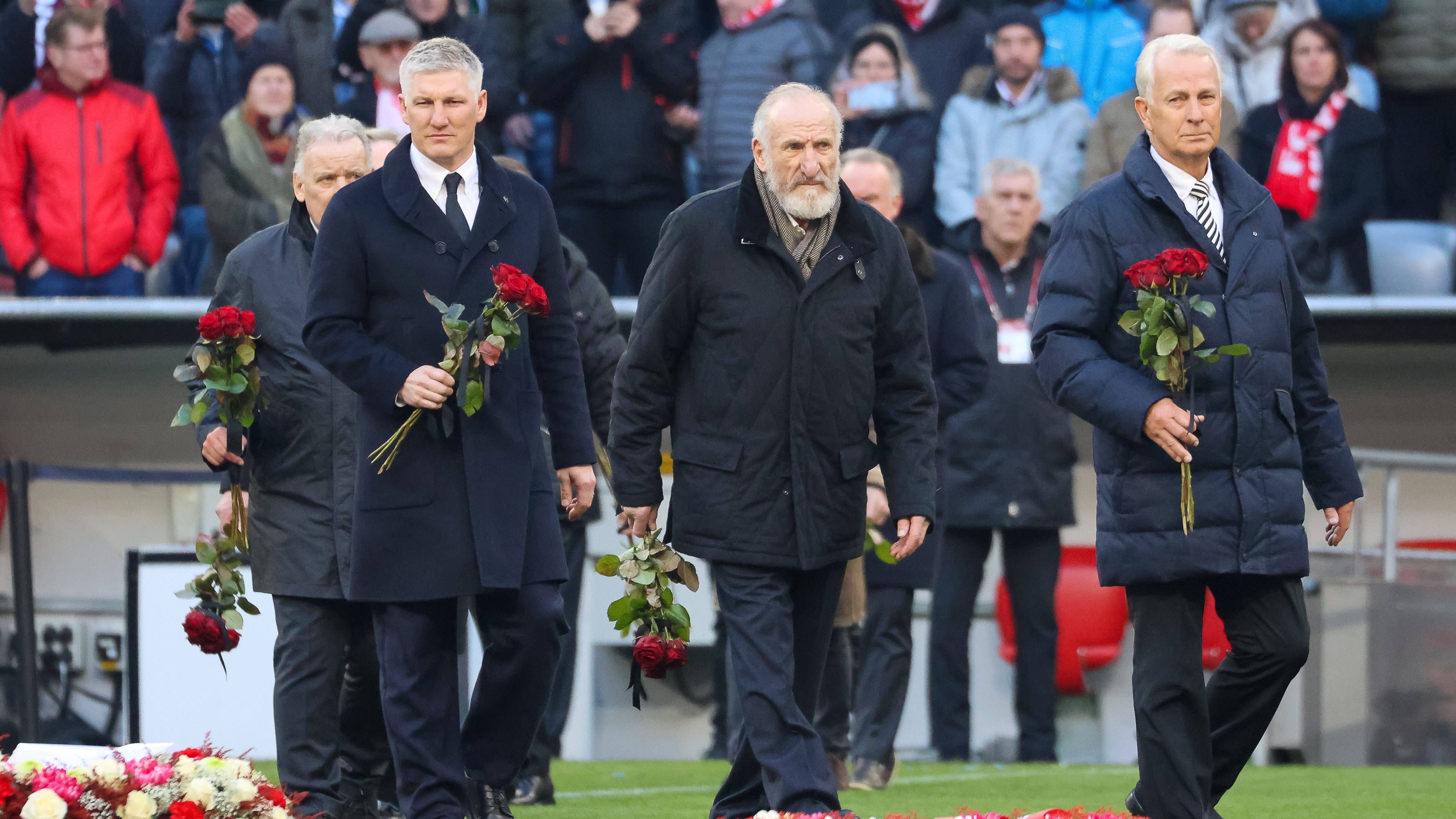 <strong>Wegbegleiter legen Blumen nieder</strong><br>Ehemalige Wegbegleiter wie Bastian Schweinsteiger, Georg "Katsche" Schwarzenbeck und Rainer Bonhof (v.l.) legen Blumen auf dem Rasen nieder.