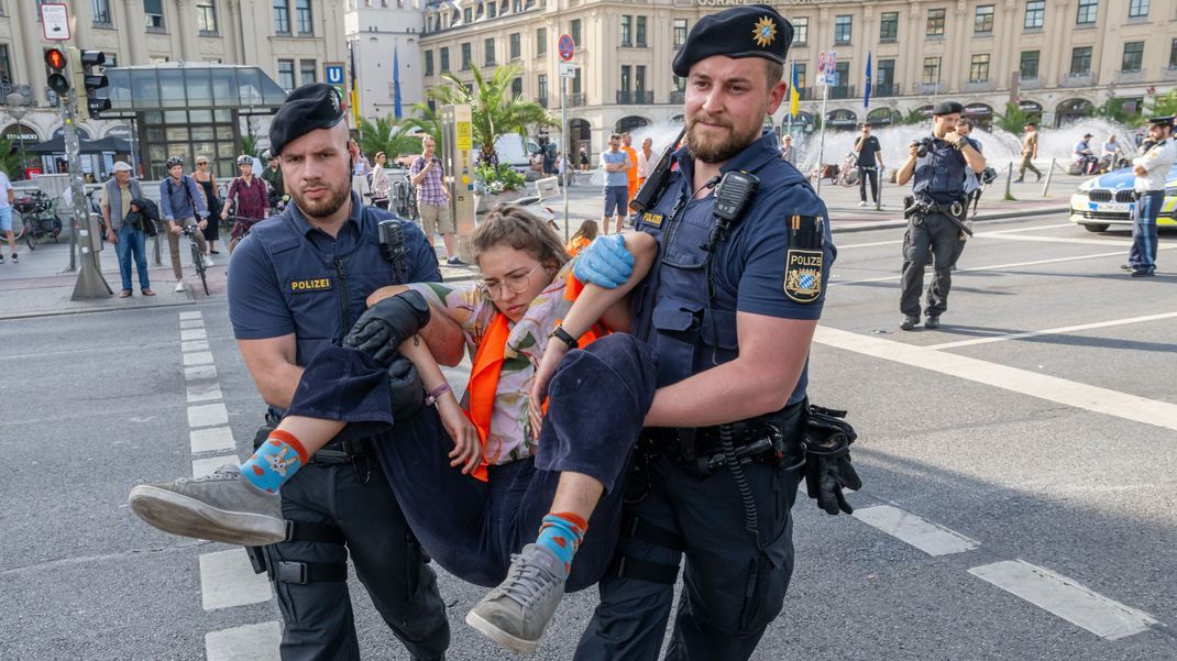 Polizisten tragen auf der Kreuzung am Stachus in der Innenstadt Aktivist:innen der "Letzten Generation" weg.