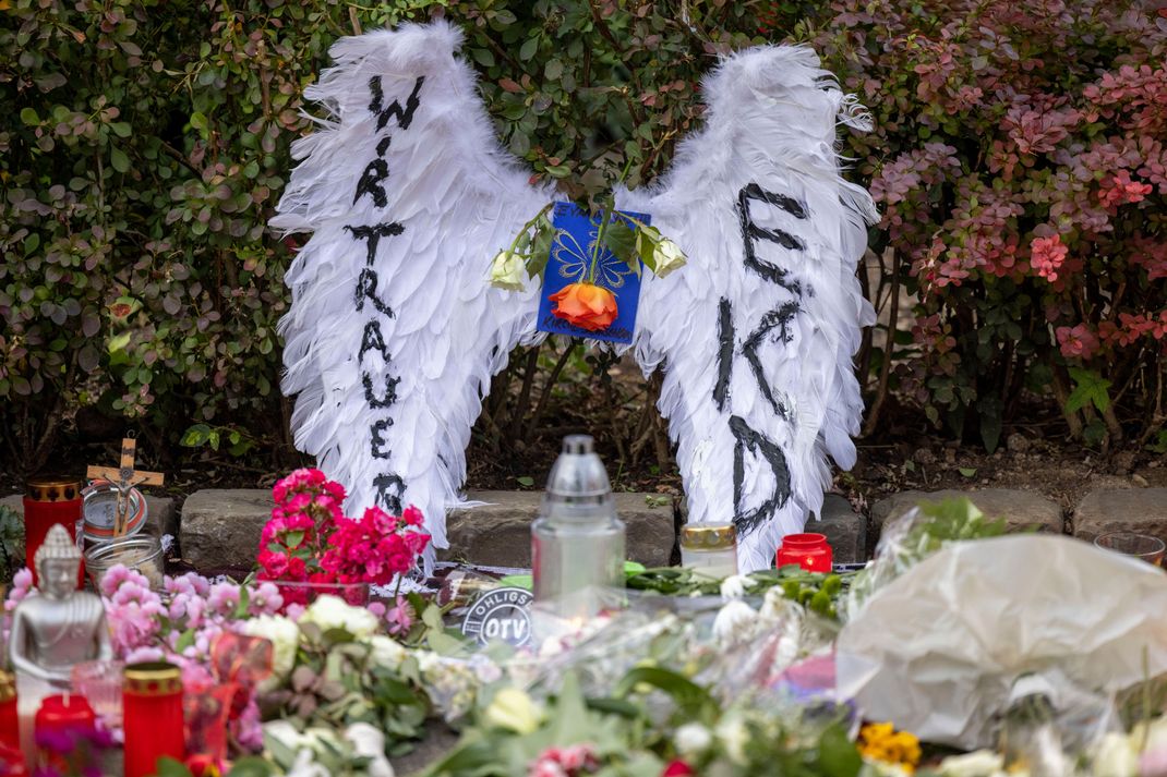 In der Nähe des Tatorts haben Menschen Blumen, Kerzen und auf Schildern selbstgemalte Botschaften niedergelegt. 