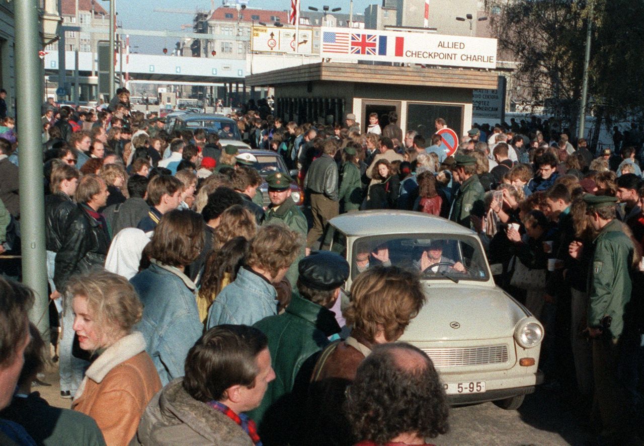 Am Grenzübergang Checkpoint Charlie überquerten DDR-Bürger:innen in ihren Trabis die aufgehobene Grenze. Dort wurden sie von West-Berliner:innen begrüßt.