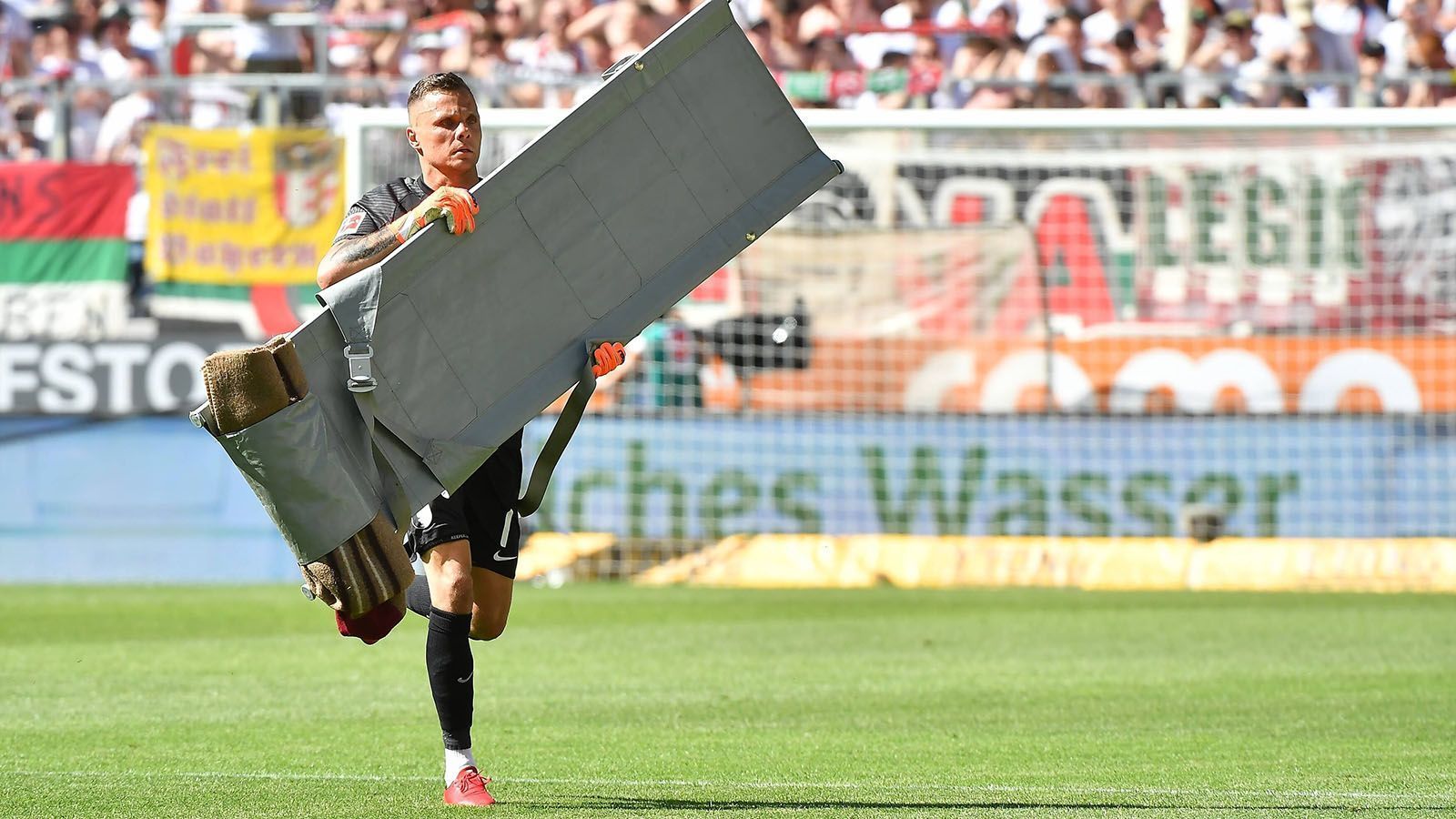 
                <strong>Weil die Ärzte zu lange brauchten: Rafal Gikiewicz schnappt sich Trage</strong><br>
                Nachdem der Fürther Jessic Ngankam mit Niklas Dorsch bei einem Kopfballduell zusammenprallt, bleibt der Augsburger zunächst liegen. Die Ärzte lassen sich wohl ein wenig zu viel Zeit. Dieser Meinung scheint zumindest Rafal Gikiewicz zu sein. Der Torhüter der "Fuggerstädter" schnappt sich die Trage der Sanitäter, eilt zu seinem Teamkollegen und hilft, Dorsch auf die Trage zu legen.
              