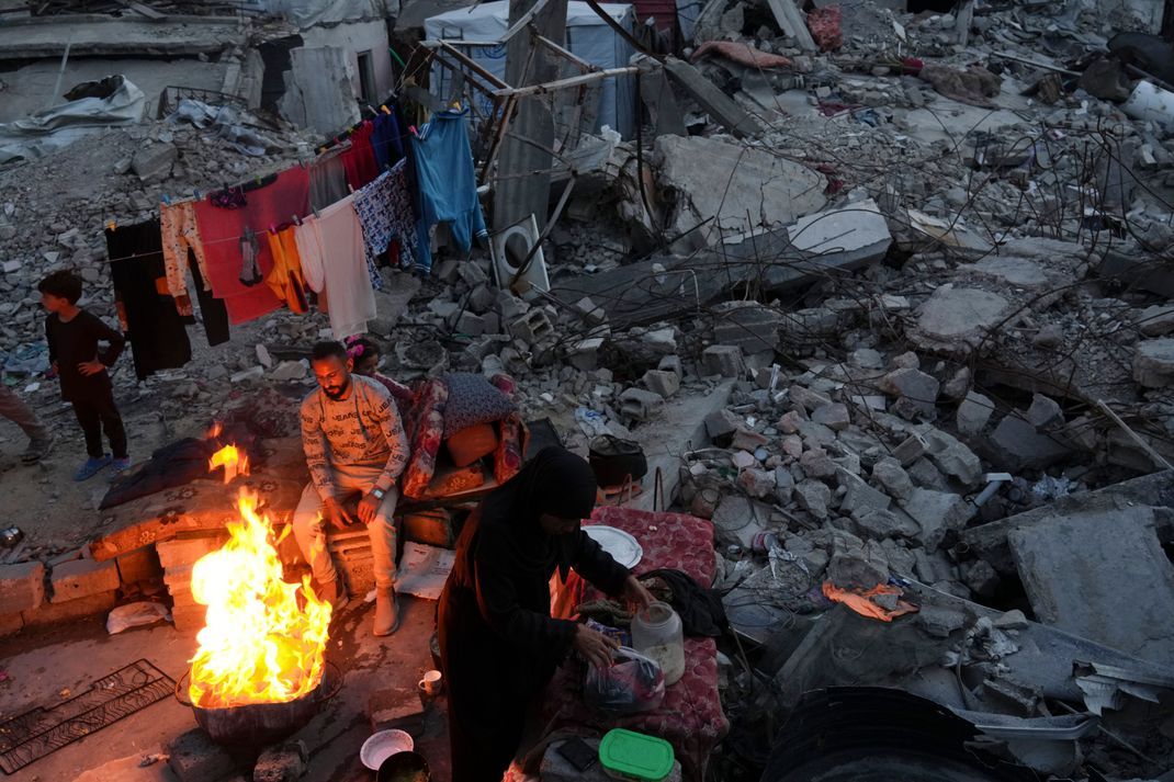 Mitglieder der palästinensischen Familie Marouf kochen vor ihrem durch die Luft- und Bodenoffensive der israelischen Armee zerstörten Haus in Dschabalija.