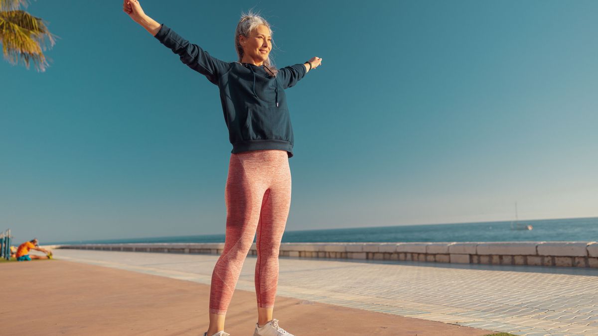 Frau macht draußen am Meer Sport und atmet