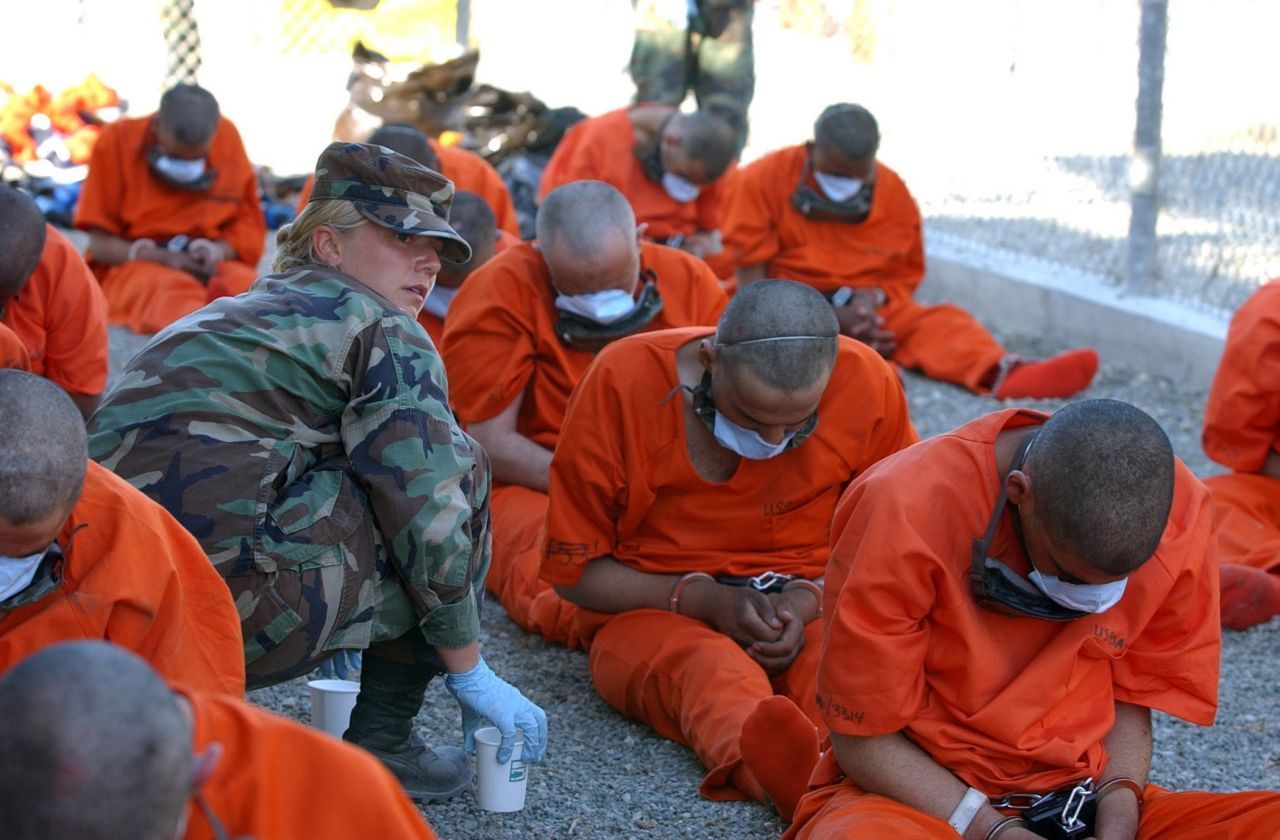 Eine Frau des US-Militär versorgt angekettete Häftlinge mit Wasser, als diese im Camp X-Ray auf der Guantanamo Bay Naval Base ankommen.