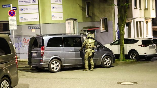 Ein Polizist steht während der Mafia-Razzia in Hagen an einem Van.