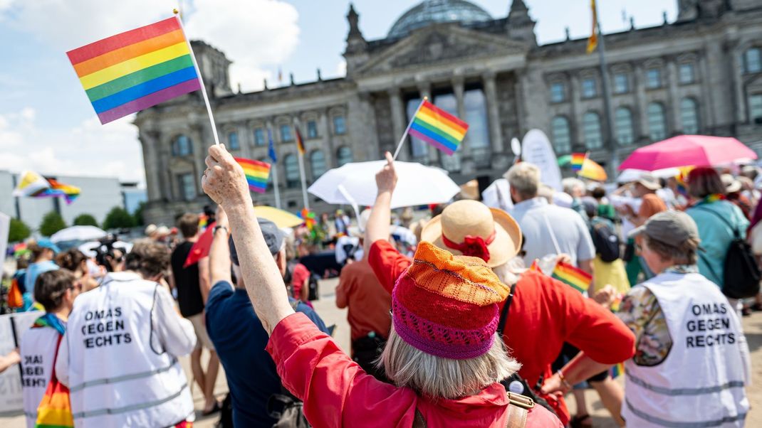 Berlin: Eine Frau hebt bei der Demonstration "Bun(T)estag für alle. Kundgebung unter dem Regenbogen für das Grundgesetz" vor dem Reichstagsgebäude eine Regenbogenflagge.