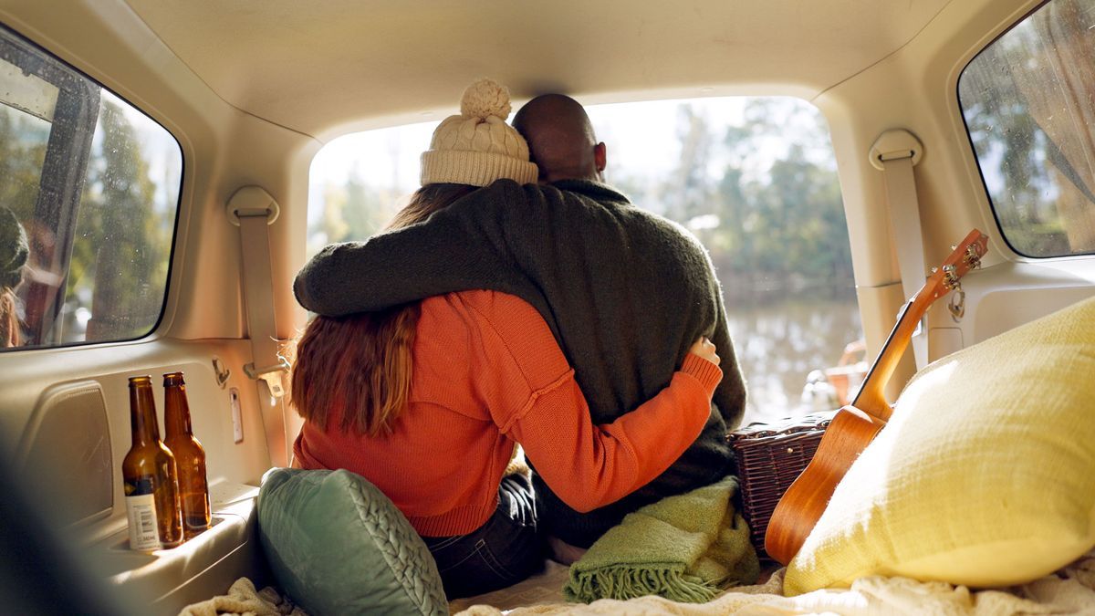 Hug, winter and a couple in a car for a road trip, date or watching the view together. Happy, travel and back of a man and woman with an affection in transport during a holiday or camping in nature