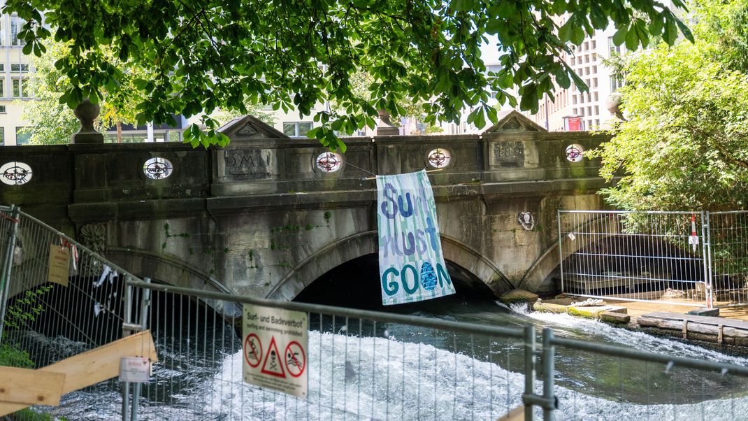 Ein Banner mit der Aufschrift «Surf must go on» hängt an der Eisbachbrücke an der Eisbachwelle.