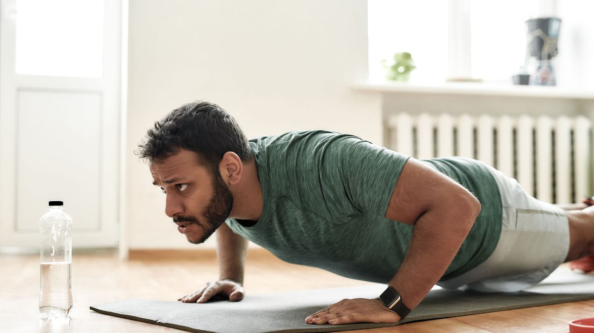 Fight for fit body. Young active man looking focused, exercising, doing push ups during morning workout at home. Sport, healthy lifestyle