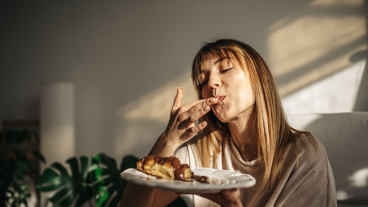 Attractive girl eating croissants in a bright room. Beautiful girl eating croissants with chocolate for breakfast