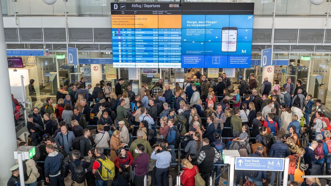 Passagiere stehen in der Abflughalle in Schlangen an, um zur Sicherheitskontrolle zu gelangen.