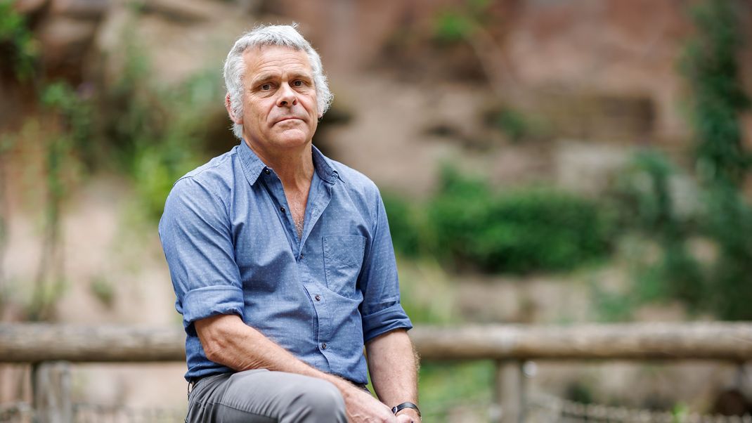Dag Encke, Direktor des Tiergarten Nürnberg, sitzt vor einer Außenanlage.