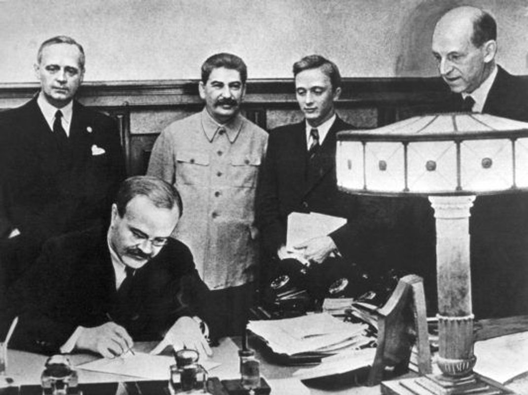 Am 23. August 1939 unterzeichneten Joachim von Ribbentrop (links), Außenminister des Deutschen Reiches, und der sowjetische Außenminister Wjatscheslaw Molotow (vorne) in Moskau den Nichtangriffspakt. Neben Ribbentrop steht Josef Stalin (Mitte), daneben von rechts die Diplomaten Wladimir Pawlow und Friedrich Gaus.