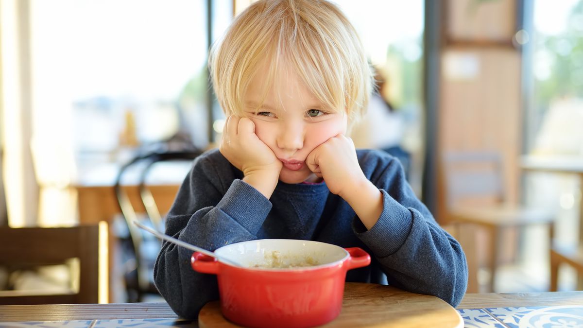 Little child sitting the table in cafe or restaurant and doesn't want to eat. Healthy food. Kids diet. Poor appetite.