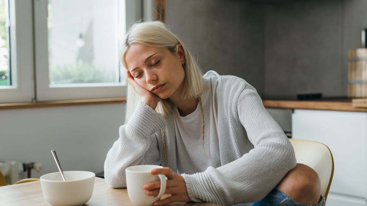 sleepy caucasian woman drinking morning coffee in her kitchen