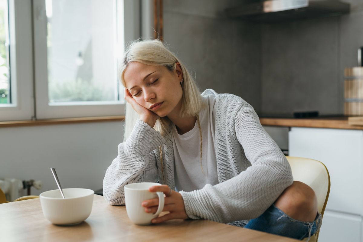 sleepy caucasian woman drinking morning coffee in her kitchen