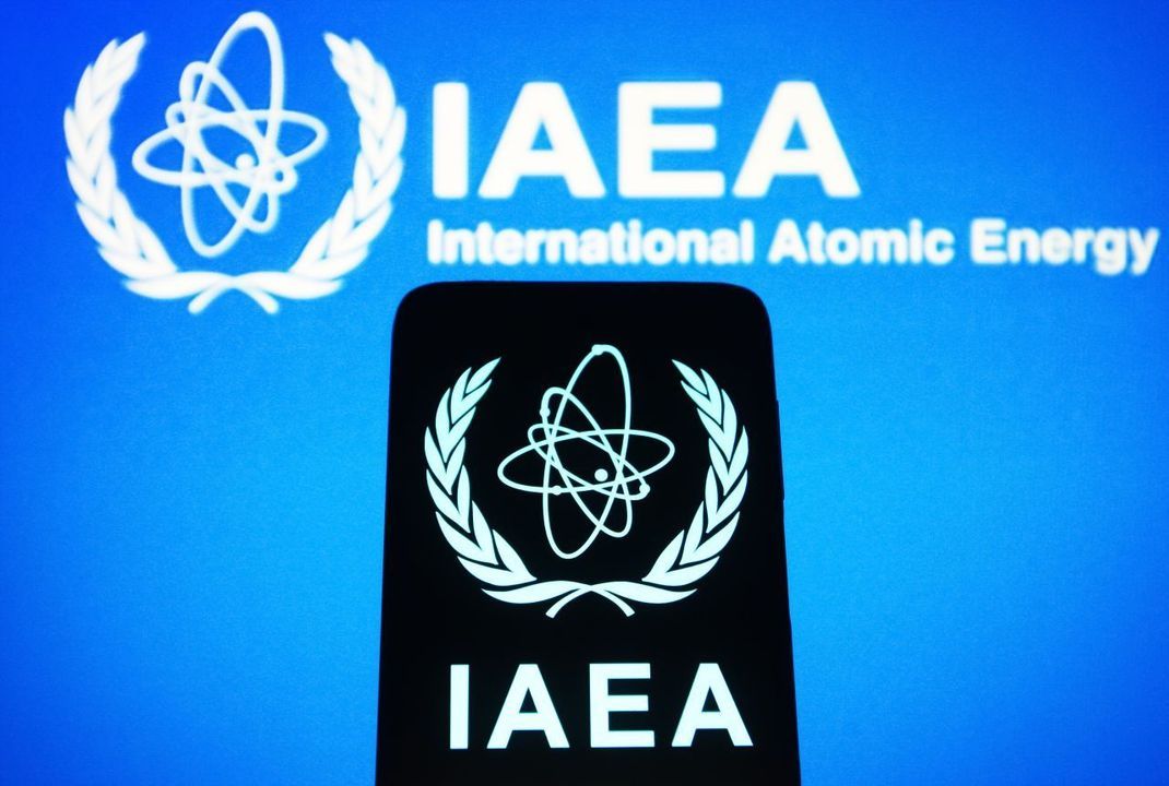 Das Logo der IAEA besteht aus dem Atom-Symbol mit mehreren überlagerten Ellipsen, der Abkürzung IAEA und dem vollen Namen der Organisation.