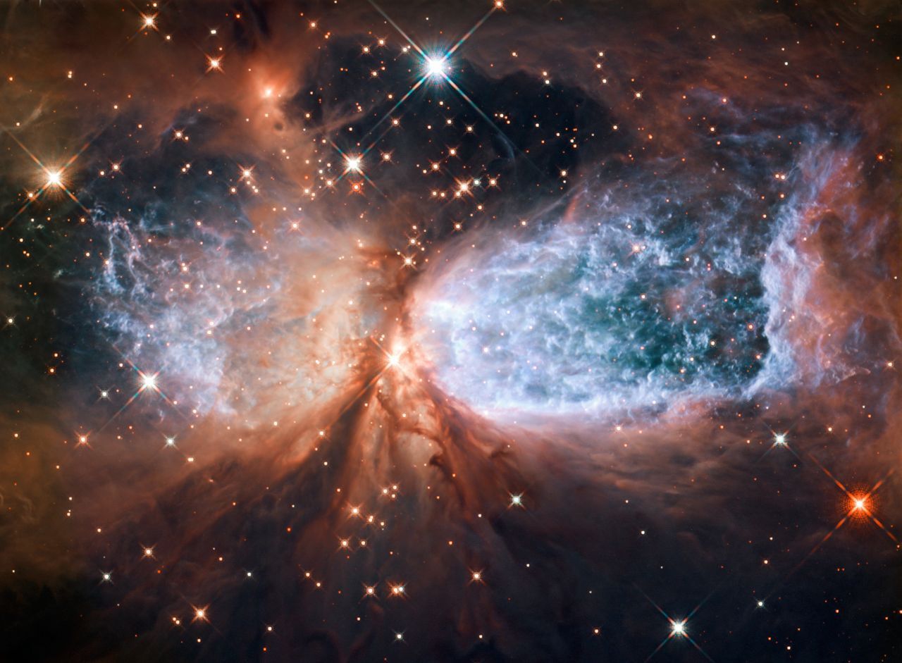 Dieses Bild zeigt H 2-106. Eine Region im All, die Sterne zur Welt bringt. In der Mitte entsteht gerade so ein Stern. Bei der Entstehung schießen unendlich viele Partikel ins Weltall. Zu sehen zum Beispiel am Wasserstoff, der hier blau dargestellt wird.