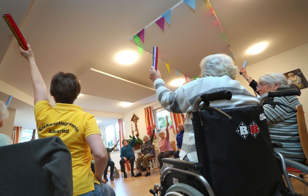 Seniorinnen sitzen gemeinsam in einer Demenz-Wohngemeinschaft bei einer angeleiteten Sitzgymnastik.  (Archivbild)