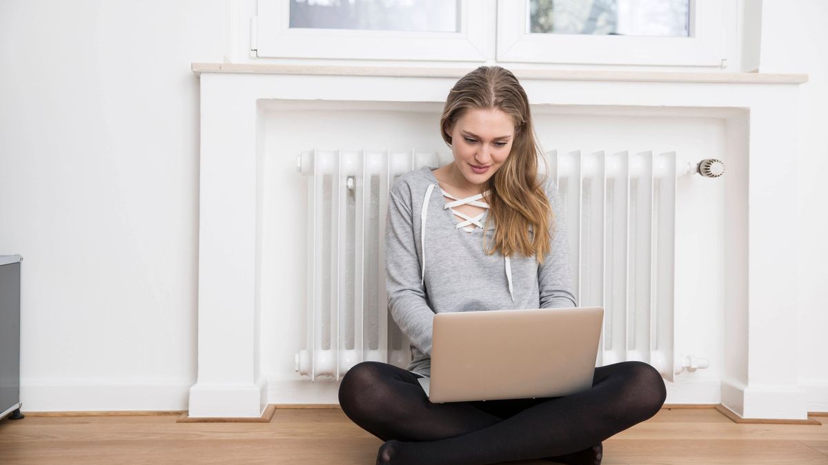 Kälte Winter Wohnung Frau mit Laptop vor der Heizung 83437358