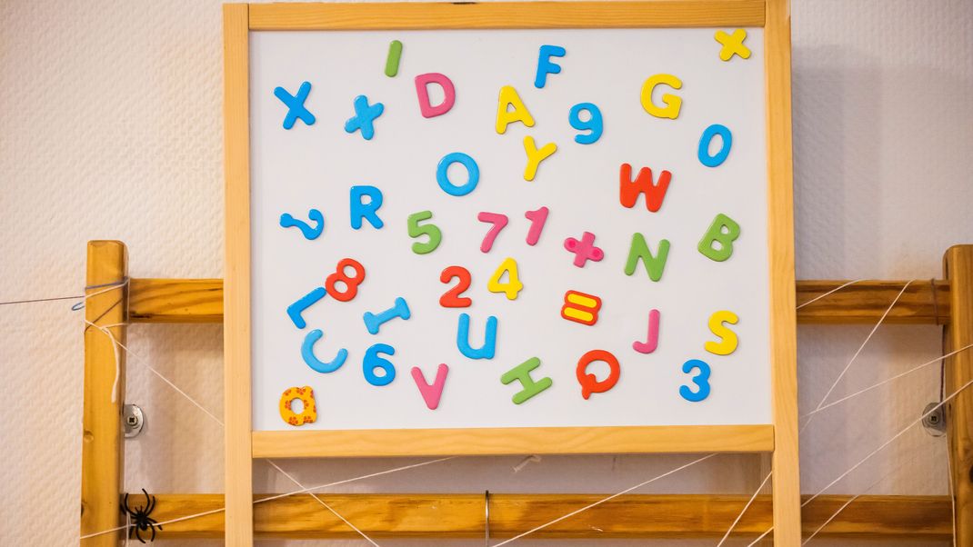 Eine Tafel mit Buchstaben und Zahlen in einer Kita. 