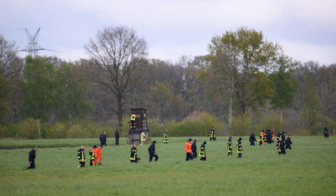  Einsatzkräfte der Polizei und Feuerwehr auf einem Feld im Einsatz. 