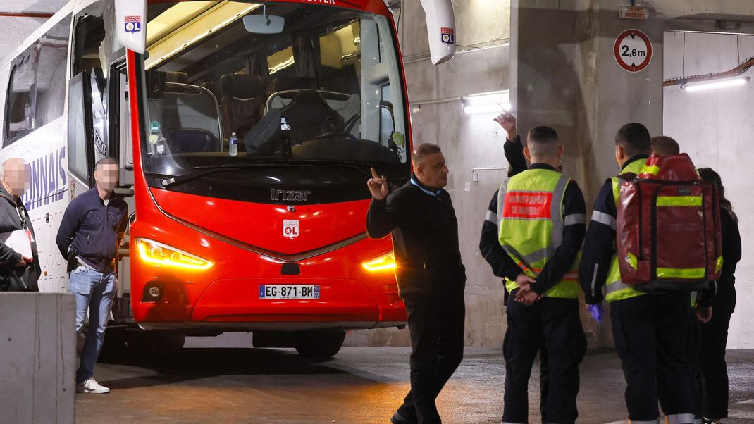 Feuerwehrleute stehen neben dem Mannschaftsbus von Olympique Lyon.