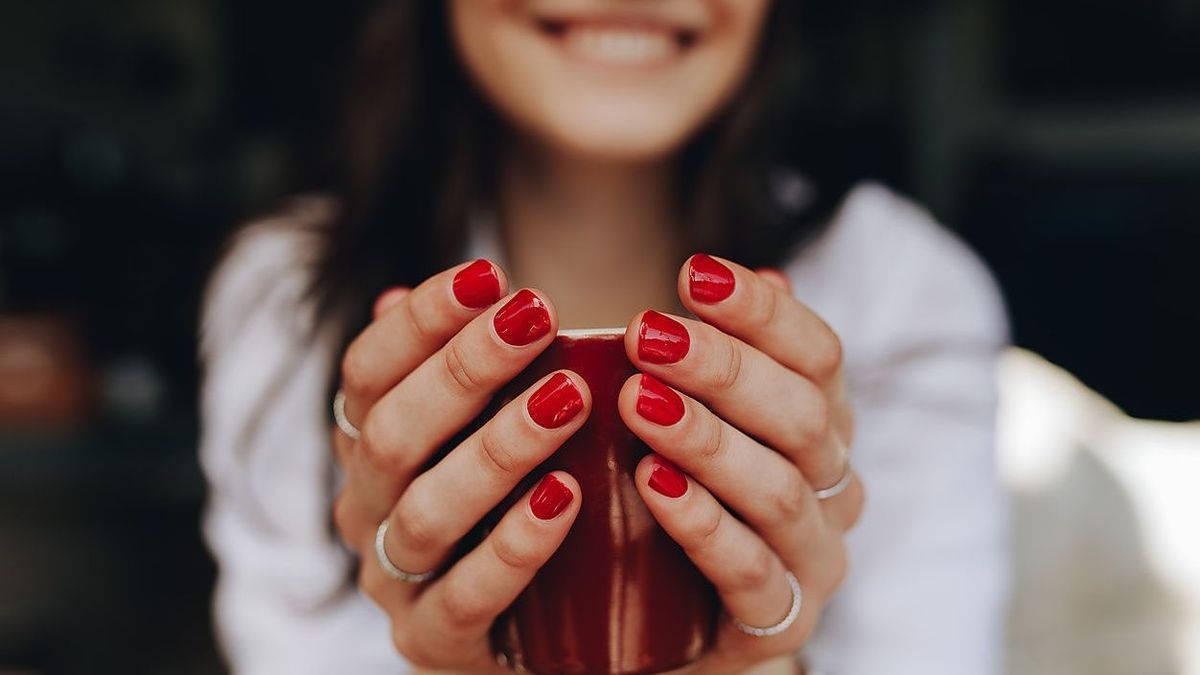 Close up of woman hands holding a coffee cup. Female with coffee cup sitting at cafe. Focus on female hands with coffee.