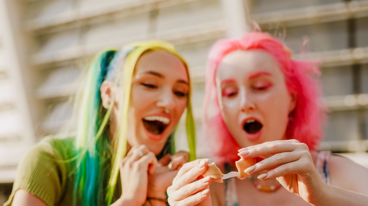 Young white women expressing surprise while eating fortune cookie