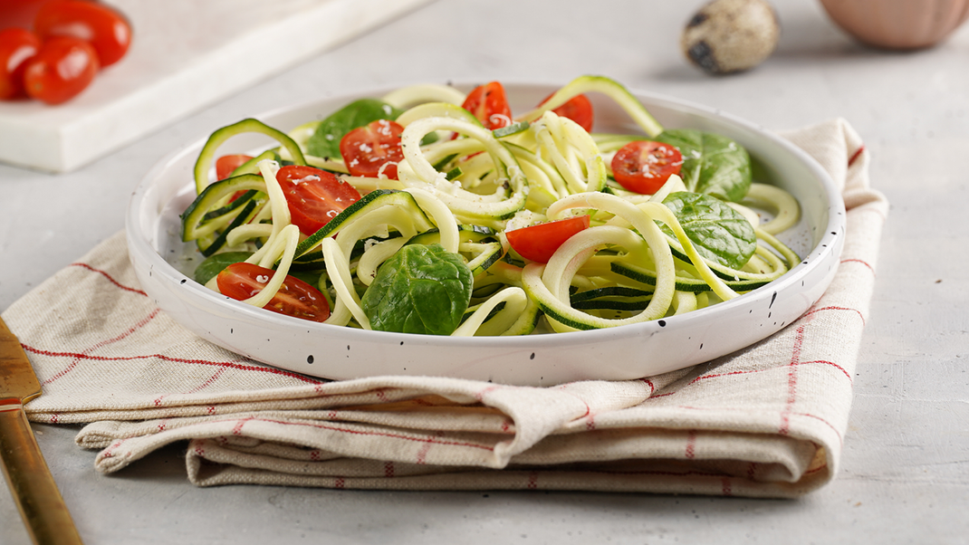 Selbst gemachte Zoodles mit aromatischen Tomaten und frischem Basilikum. Mit Mozzarella als Topping schmeckt's unwiderstehlich!