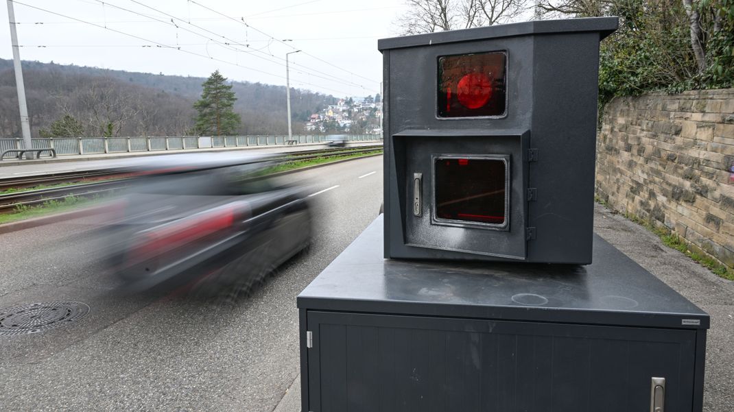 Ein Auto fährt auf einer Zufahrtsstraße an einem Blitzer zur Geschwindigkeitskontrolle vorbei.