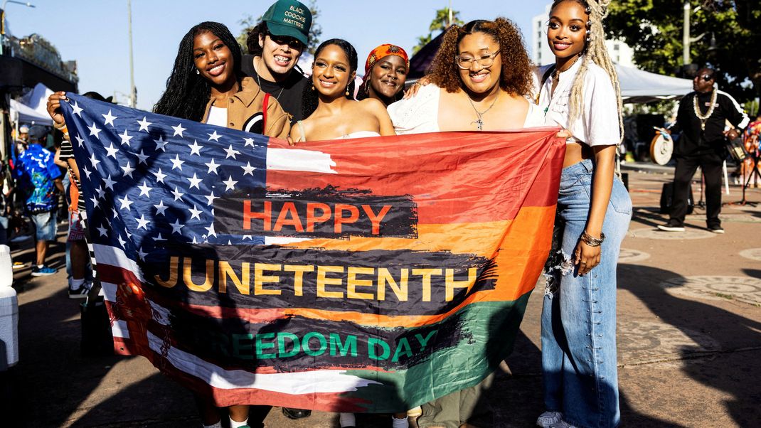 Menschen posieren für ein Foto während einer Veranstaltung zum Juneteenth 2024 im Leimert Park in Los Angeles, USA.